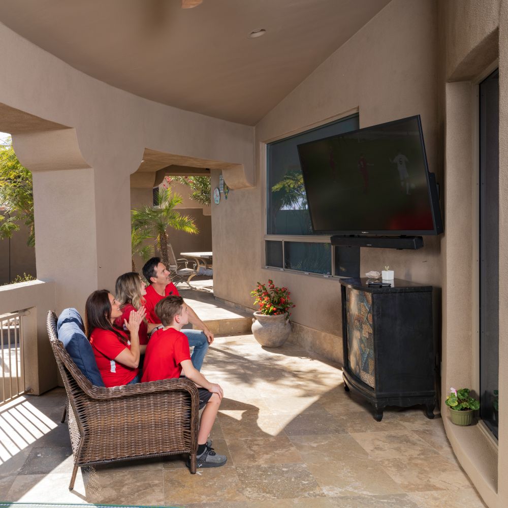 Family watching a Furrion outdoor TV, enjoying outdoor audio parts and accessories